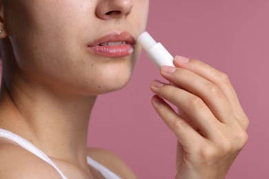 Photo of Young woman with lip balm on pink background, closeup
