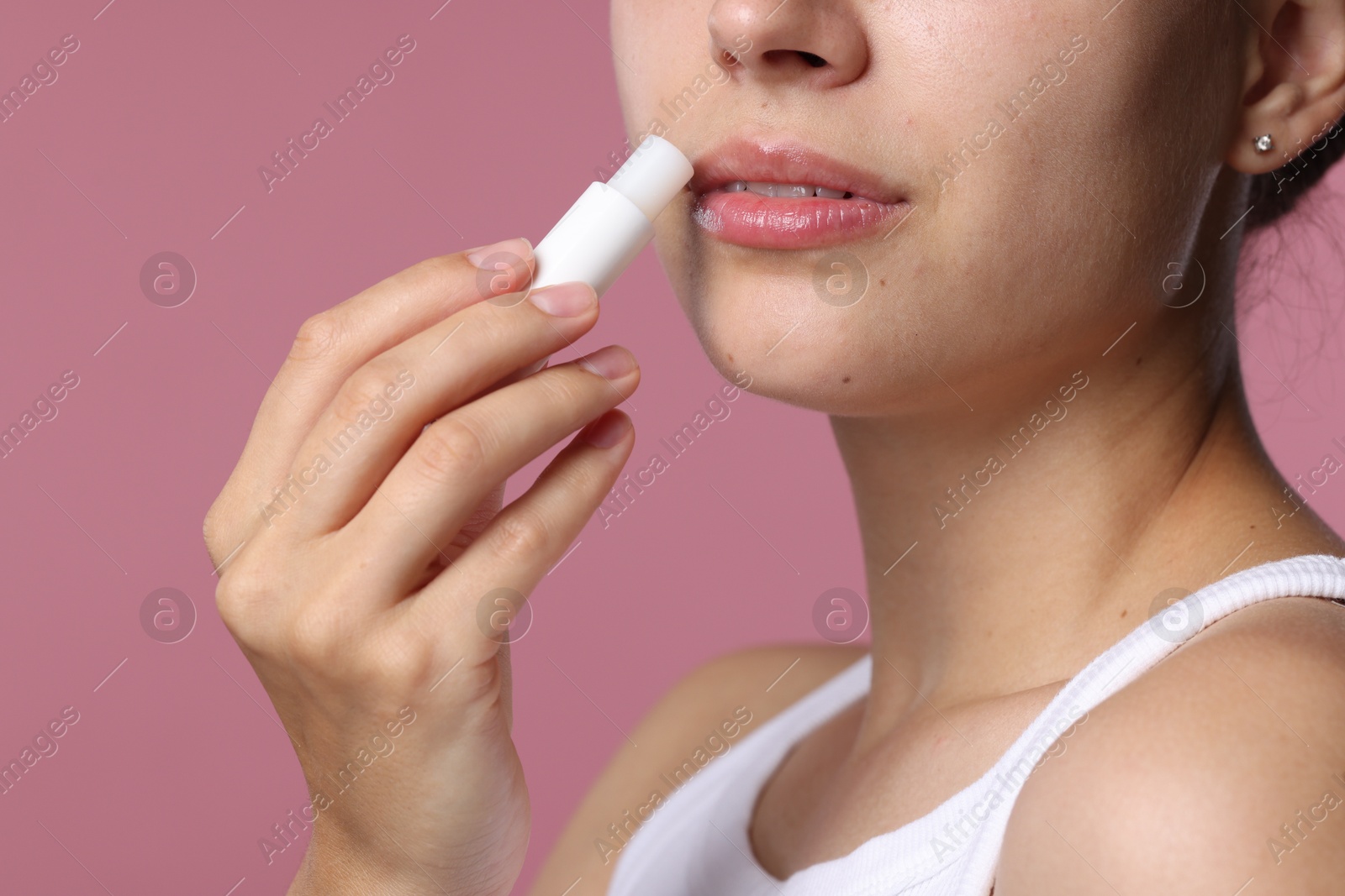 Young woman with lip balm on pink background, closeup Photo of Young woman with lip balm on pink background, closeup
