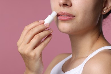 Photo of Young woman with lip balm on pink background, closeup