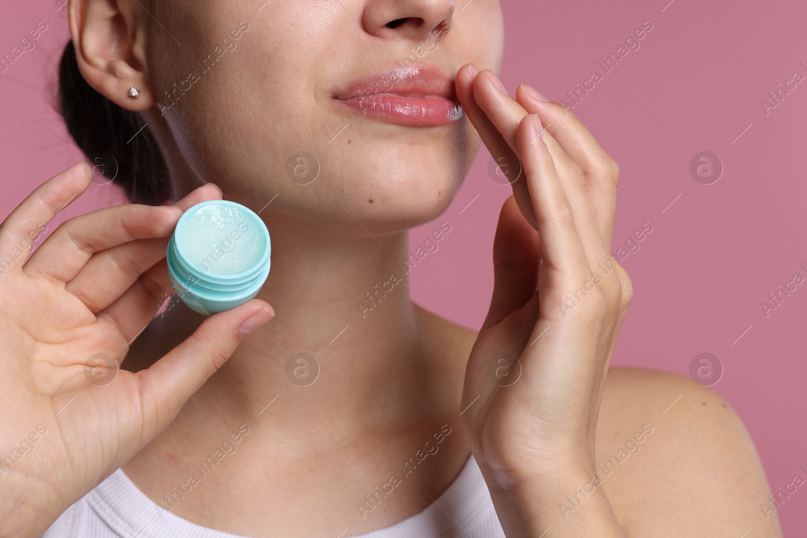 Photo of Young woman with lip balm on pink background, closeup