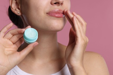 Photo of Young woman with lip balm on pink background, closeup