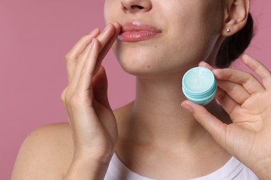Photo of Young woman with lip balm on pink background, closeup