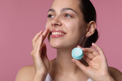 Photo of Young woman with lip balm on pink background