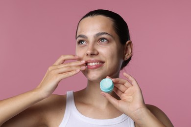 Photo of Young woman with lip balm on pink background