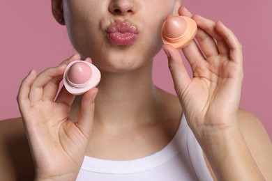 Photo of Young woman with lip balms on pink background, closeup