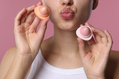 Photo of Young woman with lip balms on pink background, closeup
