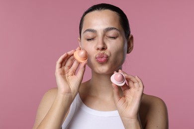 Photo of Young woman with lip balms on pink background