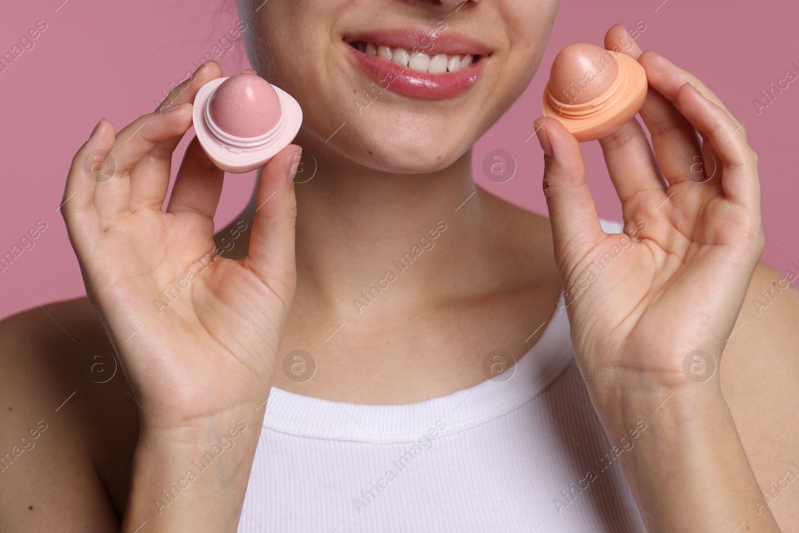 Young woman with lip balms on pink background, closeup Photo of Young woman with lip balms on pink background, closeup