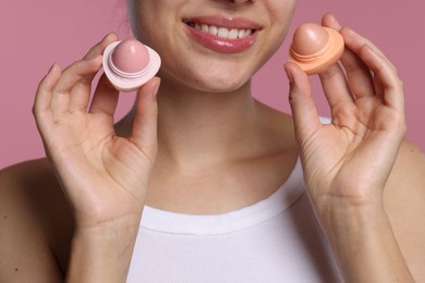 Photo of Young woman with lip balms on pink background, closeup