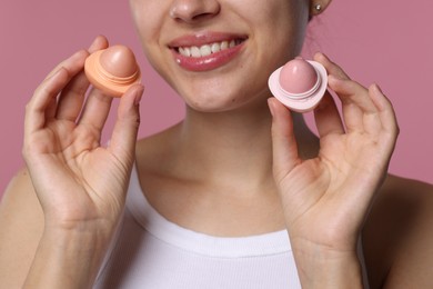 Photo of Young woman with lip balms on pink background, closeup