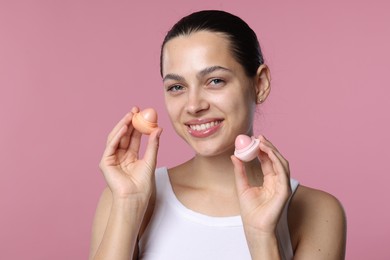 Photo of Young woman with lip balms on pink background