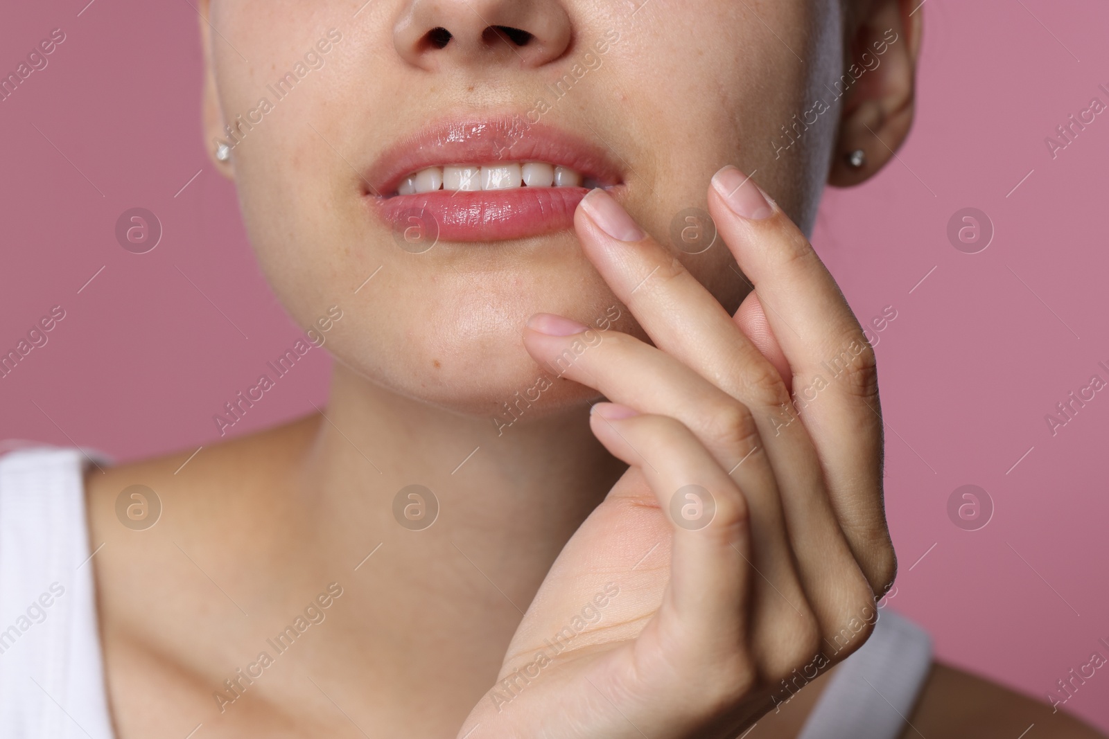 Young woman with lip balm on her lips against pink background, closeup Photo of Young woman with lip balm on her lips against pink background, closeup