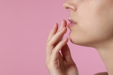 Photo of Young woman with lip balm on pink background, closeup. Space for text