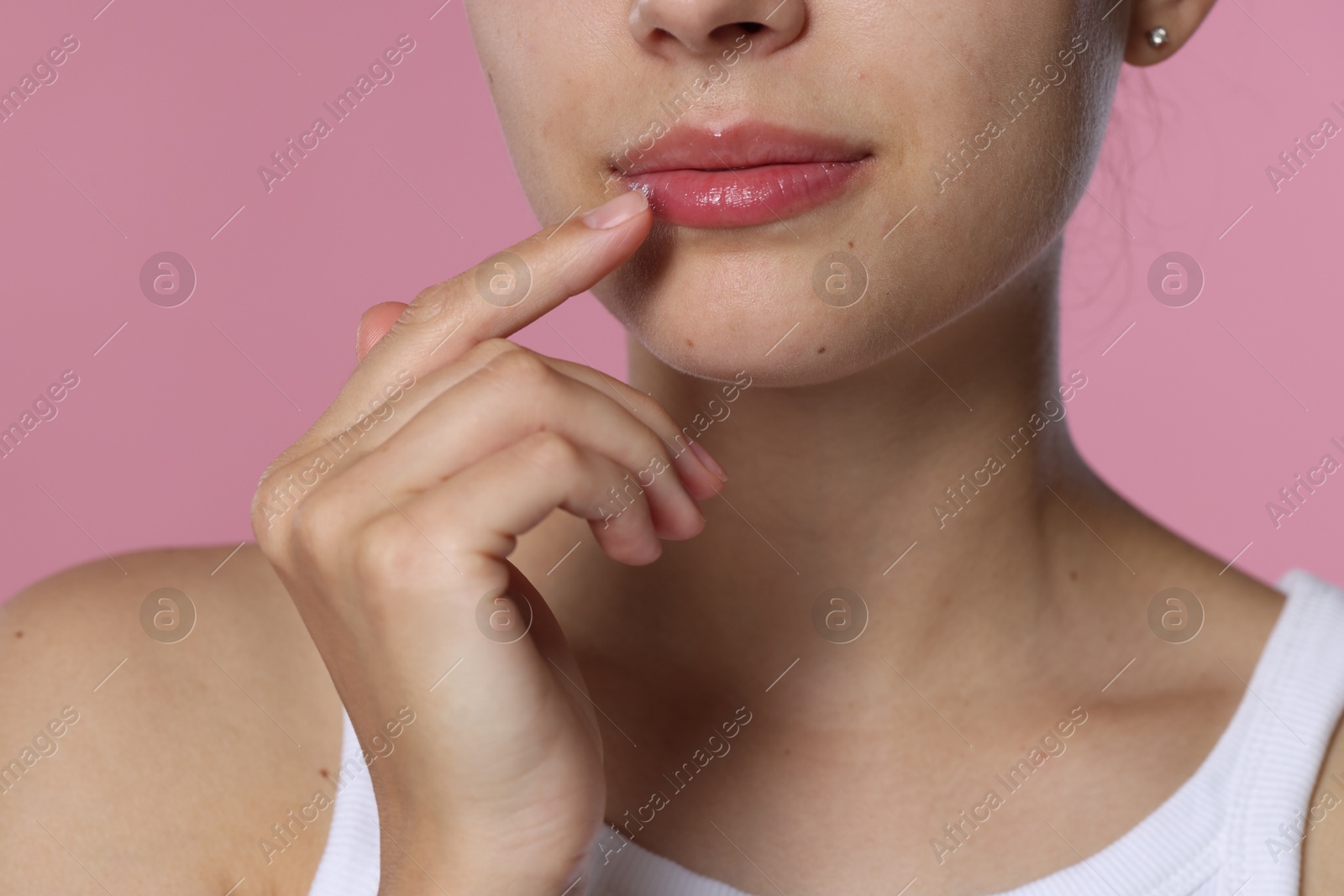 Young woman with lip balm on pink background, closeup Photo of Young woman with lip balm on pink background, closeup