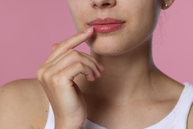 Photo of Young woman with lip balm on pink background, closeup