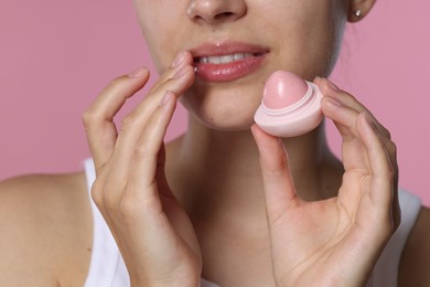 Photo of Young woman with lip balm on pink background, closeup