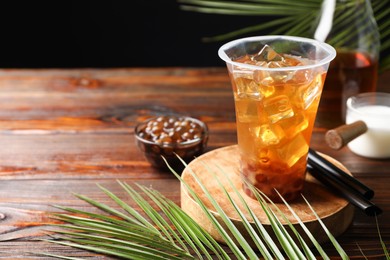 Photo of Tasty iced bubble tea and ingredients on wooden table. Space for text