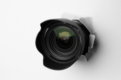 Photo of Hidden camera lens through torn hole in white paper