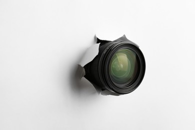 Photo of Hidden camera lens through torn hole in white paper