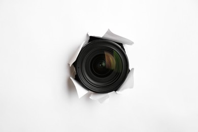 Photo of Hidden camera lens through torn hole in white paper