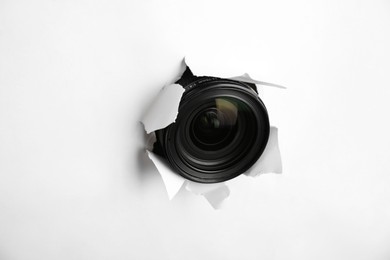 Photo of Hidden camera lens through torn hole in white paper