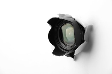 Photo of Hidden camera lens through torn hole in white paper. Space for text