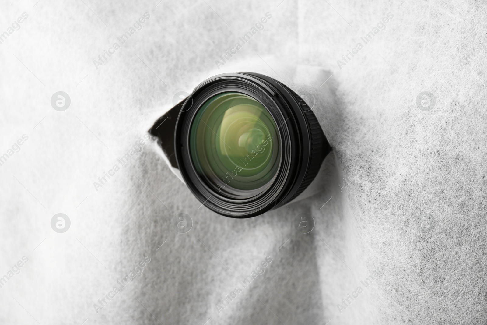 Photo of Hidden camera lens through torn hole in white fabric