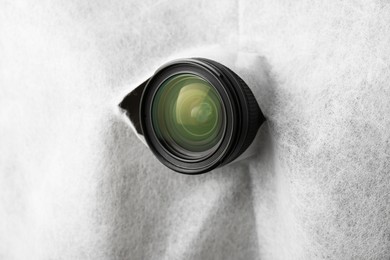 Photo of Hidden camera lens through torn hole in white fabric