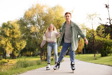 Photo of Happy couple roller skating together in park
