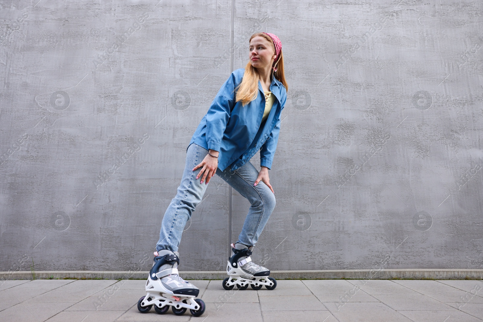 Photo of Beautiful young woman with roller skates near gray wall outdoors, low angle view