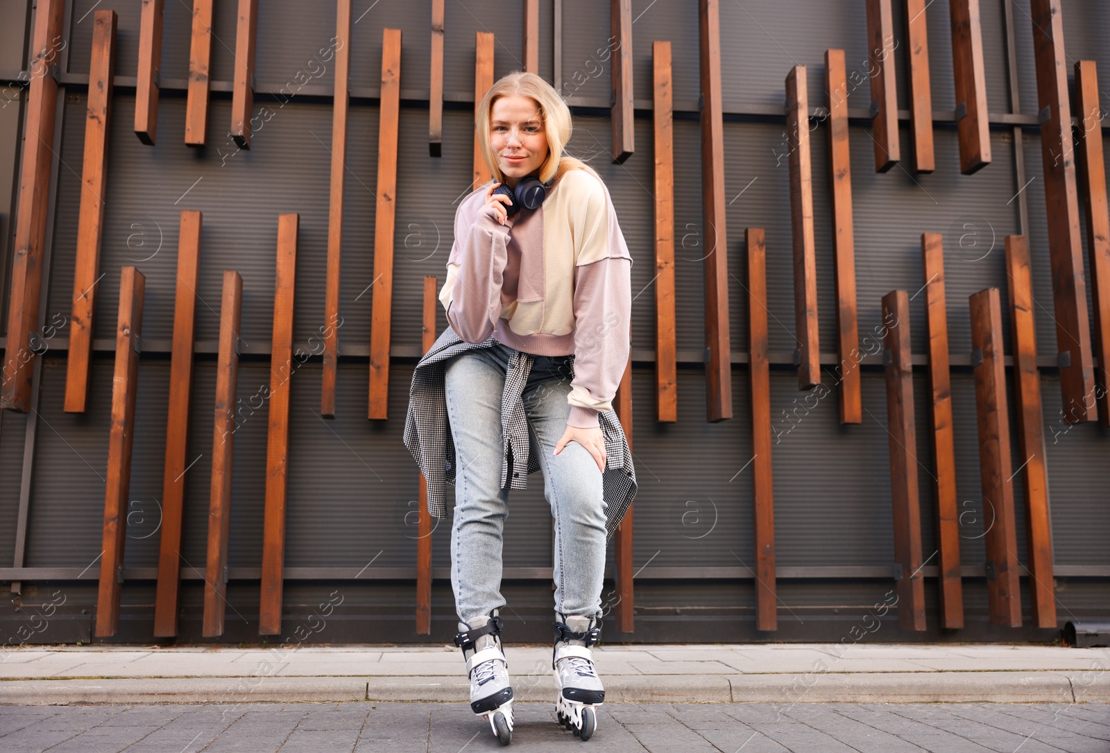 Beautiful young woman with roller skates near building outdoors, low angle view Photo of Beautiful young woman with roller skates near building outdoors, low angle view