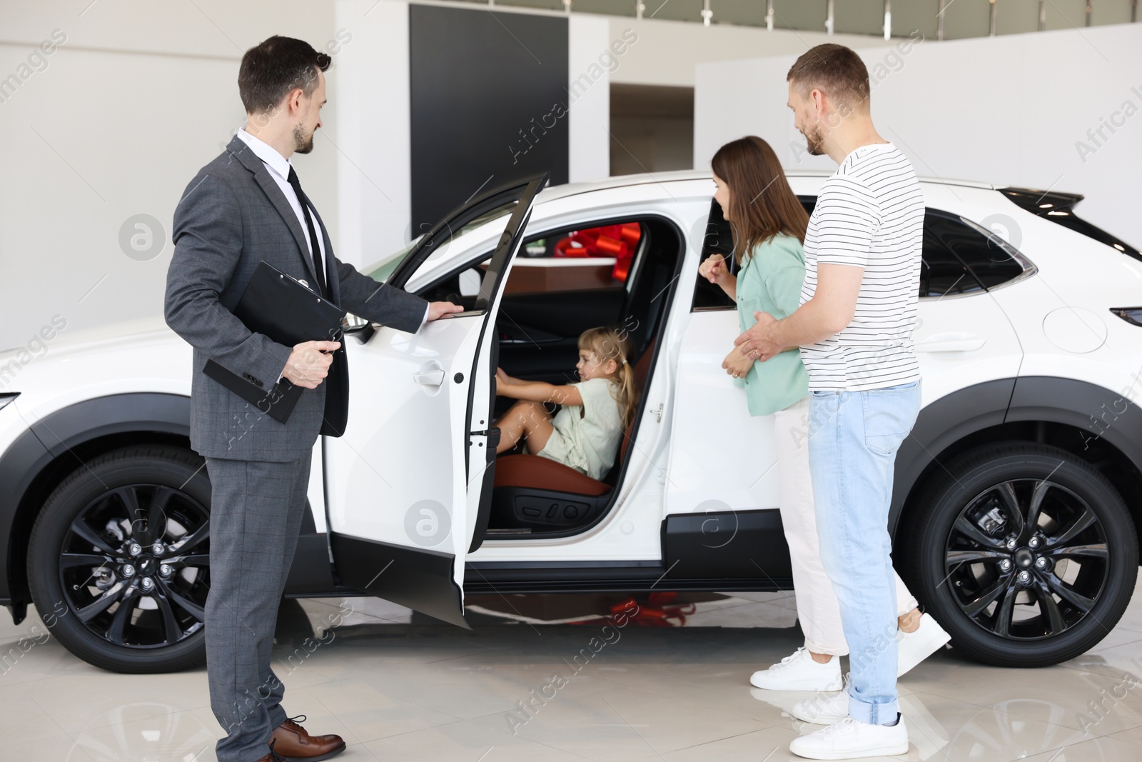 Salesman showing new car to family in salon Photo of Salesman showing new car to family in salon
