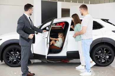 Photo of Salesman showing new car to family in salon