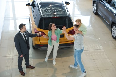 Photo of Salesman giving car key to happy family in salon