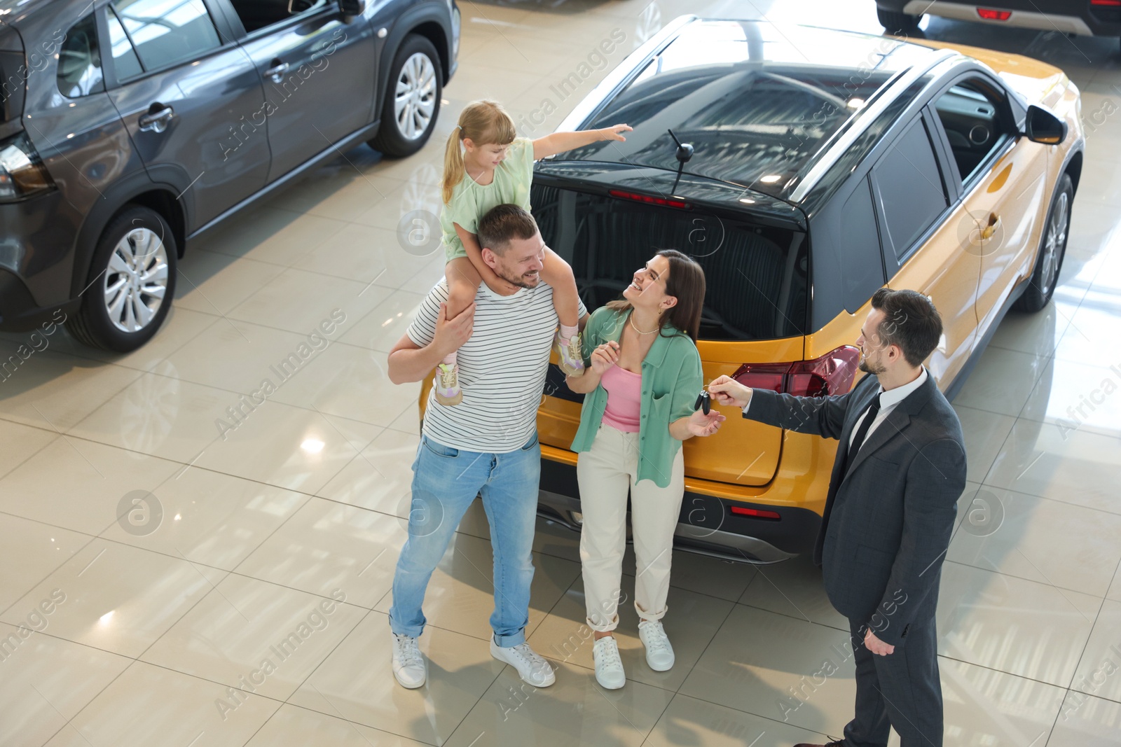 Salesman giving car key to happy family in salon Photo of Salesman giving car key to happy family in salon