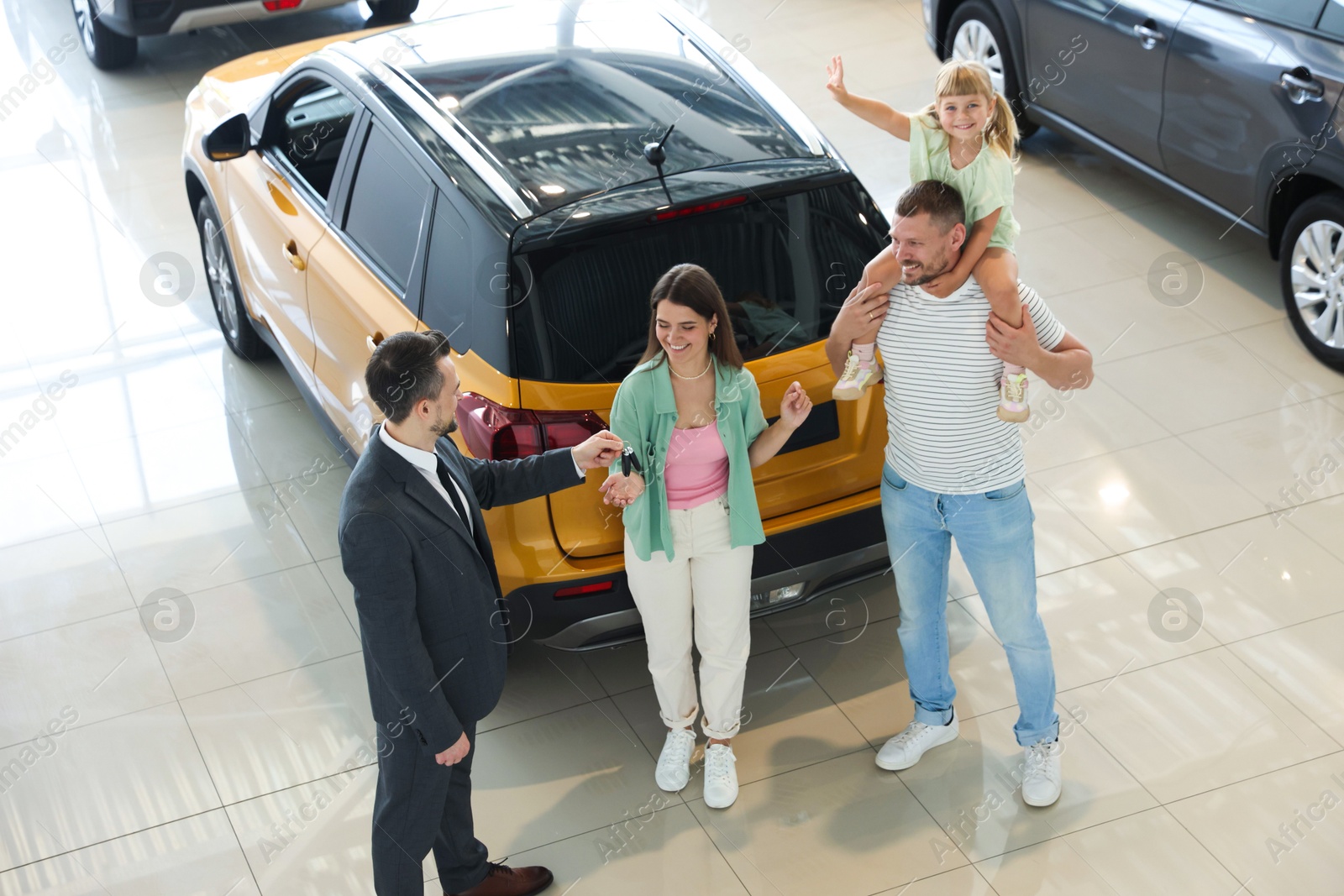 Salesman giving car key to happy family in salon Photo of Salesman giving car key to happy family in salon