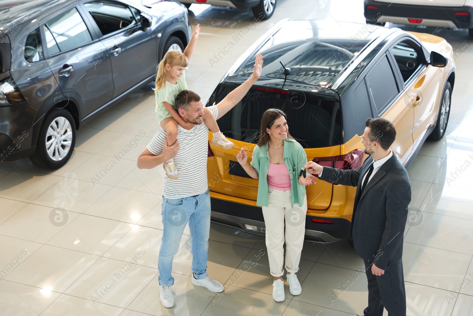 Salesman giving car key to happy family in salon Photo of Salesman giving car key to happy family in salon