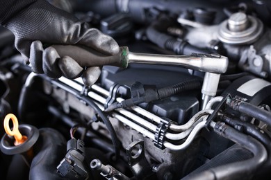 Photo of Auto parts. Professional mechanic with torque wrench fixing car indoors, closeup