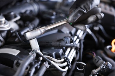 Photo of Auto parts. Professional mechanic with torque wrench fixing car indoors, closeup