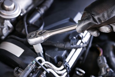Photo of Auto parts. Professional mechanic with torque wrench fixing car indoors, closeup