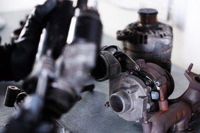 Photo of Auto parts. Professional mechanic with starter motor indoors, focus on turbocharger