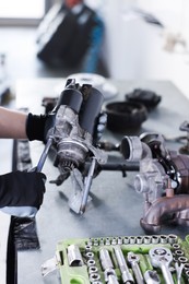 Photo of Auto parts. Professional mechanic with starter motor at grey table indoors, closeup