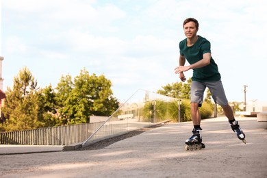 Photo of Happy man roller skating on city street. Space for text