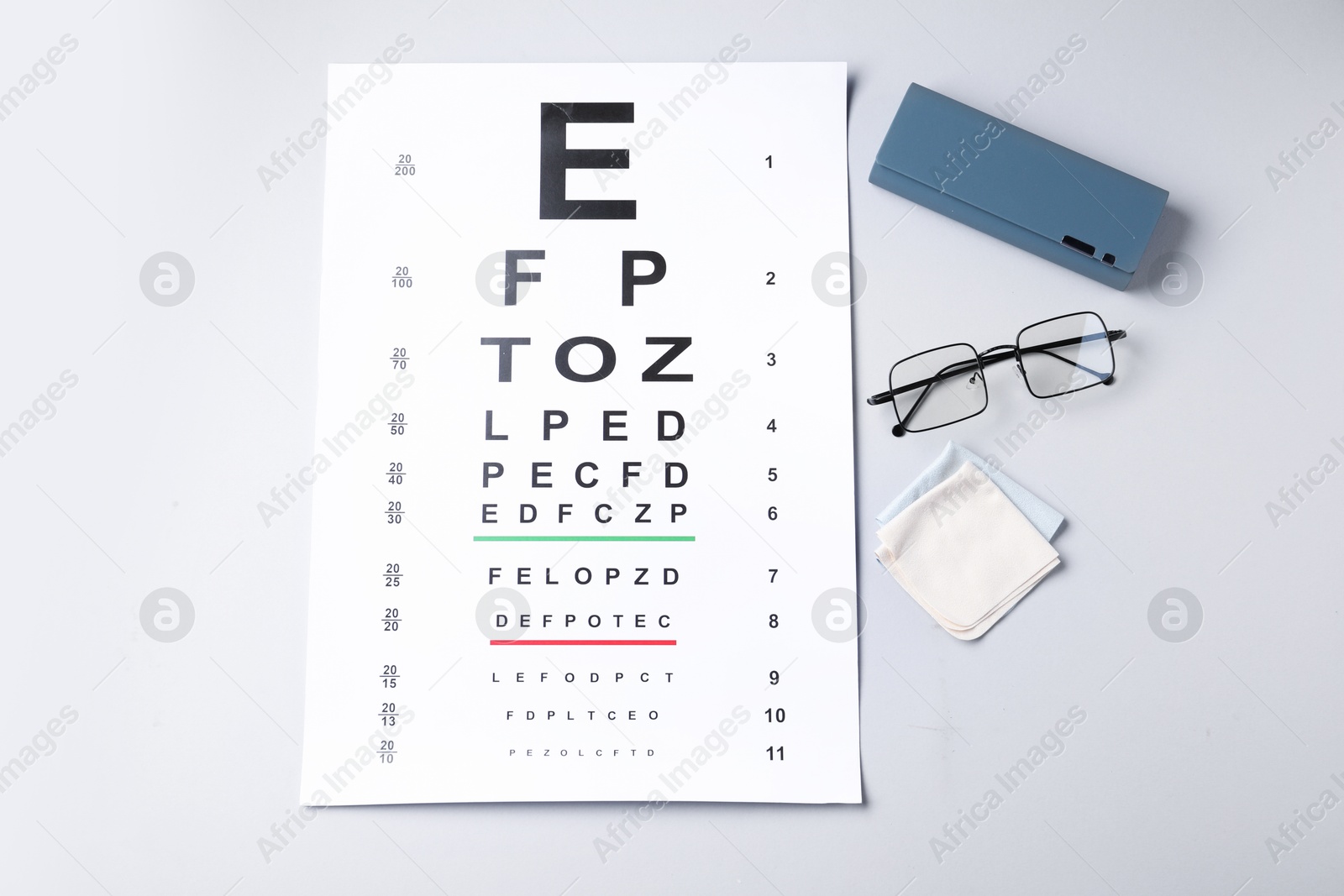 Vision test chart, glasses, case and cleaning cloth on white background, flat lay Photo of Vision test chart, glasses, case and cleaning cloth on white background, flat lay
