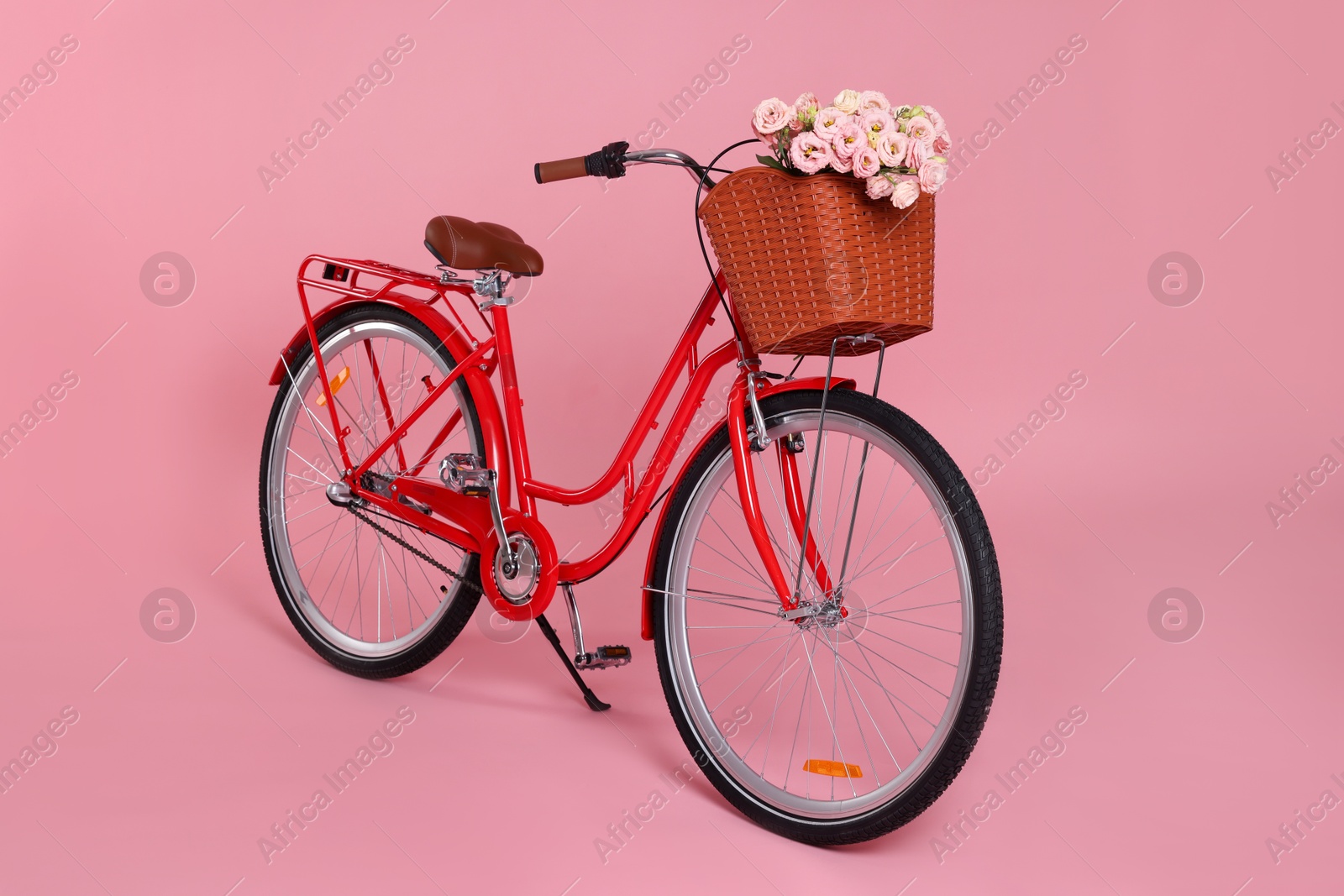 Bicycle with basket of beautiful flowers on pink background Photo of Bicycle with basket of beautiful flowers on pink background