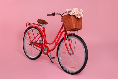 Photo of Bicycle with basket of beautiful flowers on pink background