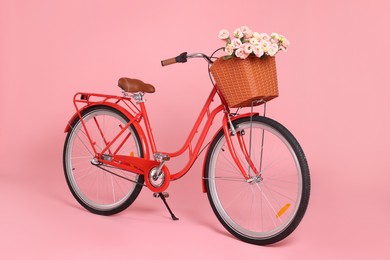 Photo of Bicycle with basket of beautiful flowers on pink background