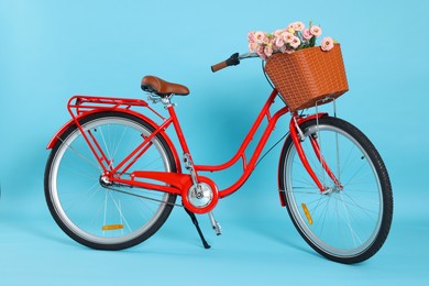 Photo of Bicycle with basket of beautiful flowers on light blue background