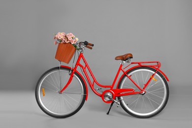 Photo of Bicycle with basket of beautiful flowers on grey background