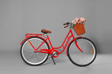 Photo of Bicycle with basket of beautiful flowers on grey background